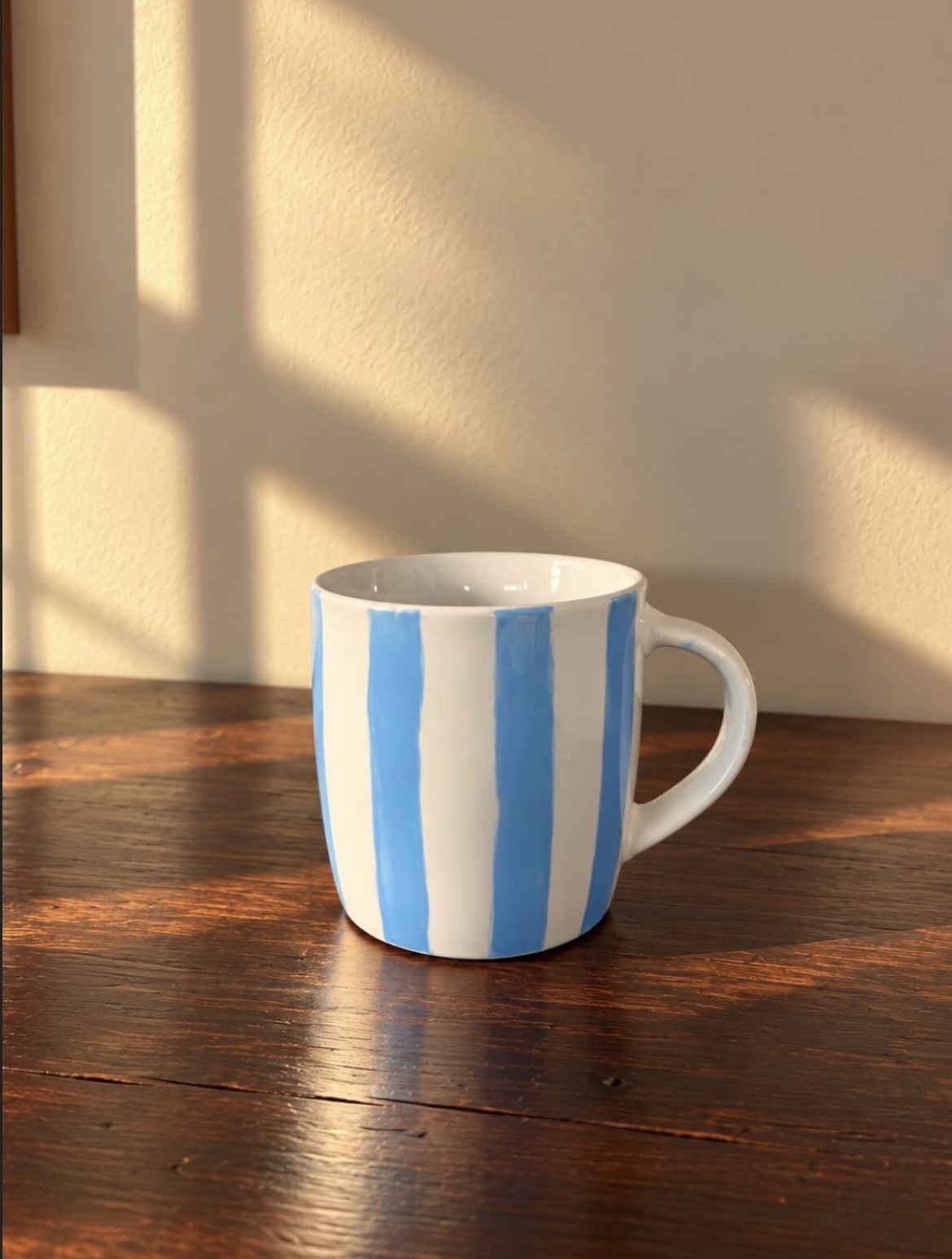 Handmålad mugg med blå randar i kvällsljus